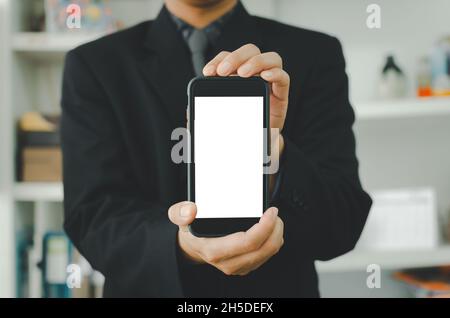 Homme d'affaires tenant un smartphone blanc à écran tactile. Utilisé pour mettre du texte ou de l'information pour annoncer des nouvelles ou vendre des produits en ligne. Concept marketin Banque D'Images