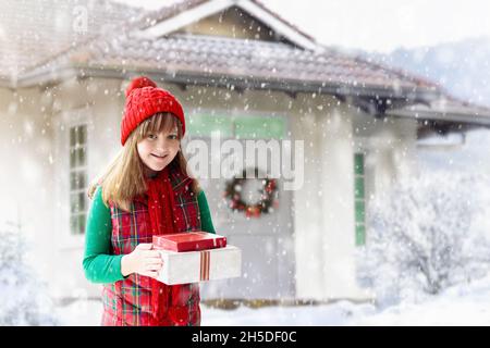 Enfant dans un chapeau rouge jouant dans la neige pendant les vacances de Noël.Cadeau de Noël en famille.En hiver, en plein air.Les enfants jouent dans un parc enneigé. Banque D'Images