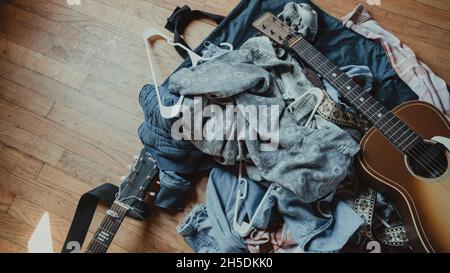 Guitare reposant sur une pile de jeans et de vestes bleus Banque D'Images