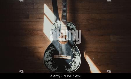 guitare noir et blanc éclairée par le soleil à travers une fenêtre - guitare sur parquet Banque D'Images