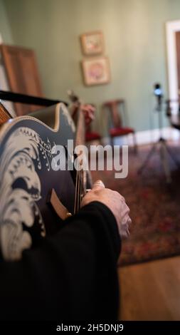 femme prenant les cordes d'une guitare noire - up-close image Banque D'Images