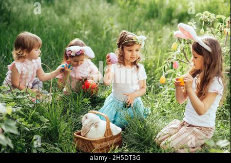 Chasse aux œufs de Pâques.Groupe d'enfants portant des oreilles de lapin courant pour ramasser des œufs colorés lors de la chasse aux œufs de Pâques dans le jardin.Tradition de Pâques.Rire des enfants dans le parc avec le concept de printemps de panier Banque D'Images