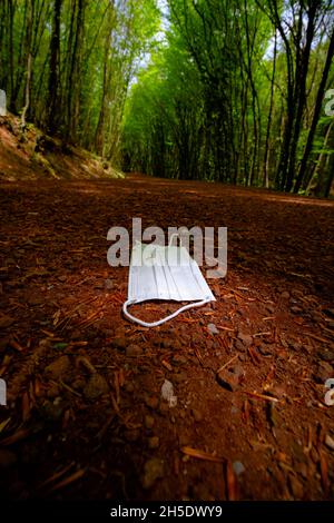 Utilisé masque de visage, masque de visage jeté à la forêt.Pollution par les risques biologiques dans les forêts.Covid-19 concept de pollution environnementale photo d'arrière-plan verticale.Sél Banque D'Images