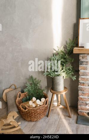 Un panier pour le bois de chauffage près de la cheminée et des branches de sapin dans un seau en étain.Ambiance chaleureuse à la maison avant Noël. Banque D'Images