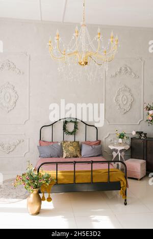 Intérieur de chambre néoclassique.Lit avec couvre-lit rose et oreillers gris.Fleurs dans un vase près du lit Banque D'Images
