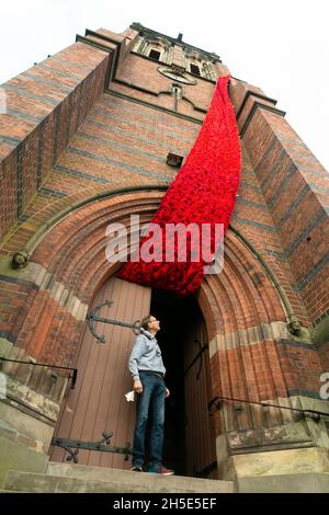 Cradley, West Midlands, Royaume-Uni.9 novembre 2021.Le gardien de l'église Paul Millward déverrouille les portes de l'église paroissiale de Saint-Pierre à Cradley, dans les West Midlands, tandis qu'une cascade de 75 mètres de coquelicots en maille orne la tour de l'église avant le dimanche du souvenir.Des milliers de coquelicots tricotés à la main ont été créés par les habitants de la région ainsi que par des contributeurs à l'étranger, et ont été l'enfant de Doreen Clifton, un résident de la région.Crédit : Peter Lophan/Alay Live News Banque D'Images