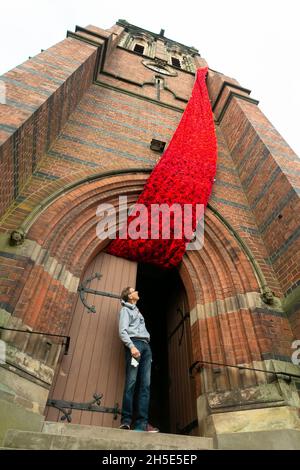 Cradley, West Midlands, Royaume-Uni.9 novembre 2021.Le gardien de l'église Paul Millward déverrouille les portes de l'église paroissiale de Saint-Pierre à Cradley, dans les West Midlands, tandis qu'une cascade de 75 mètres de coquelicots en maille orne la tour de l'église avant le dimanche du souvenir.Des milliers de coquelicots tricotés à la main ont été créés par les habitants de la région ainsi que par des contributeurs à l'étranger, et ont été l'enfant de Doreen Clifton, un résident de la région.Crédit : Peter Lophan/Alay Live News Banque D'Images