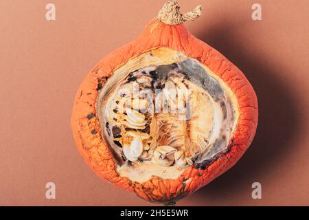 Demi-citrouille avec moule en graines sur fond marron, vue de dessus Banque D'Images