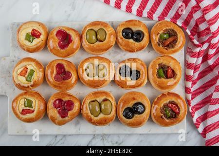 Mini hot dogs servis sous forme de buffet.Mini pizzas avec assortiment de légumes, mozzarella et basilic frais sur fond de marbre, vue rapprochée du dessus. Banque D'Images