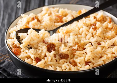 L'arroz con coco est un savoureux accompagnement colombien composé de riz, de noix de coco, de sucre, de sel et de raisins secs dans un bol sur la table. Horizontal Banque D'Images