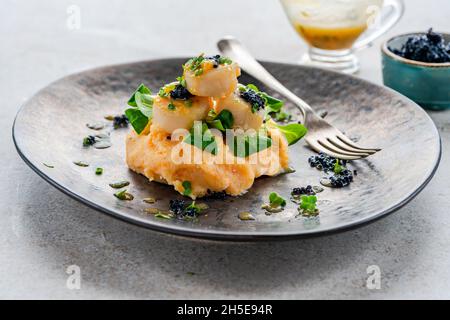 Noix de Saint-Jacques à la purée de courge musquée, au caviar et à la sauce au citron vert et au beurre Banque D'Images