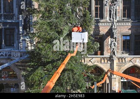 Les travailleurs sur une plate-forme élévatrice fixent l'éclairage Weihafterts au Weihaftertsbaum.Construction du marché de Noël sur Marienplatz à Munich le 9 novembre 2021. Banque D'Images