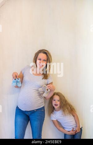 Femme enceinte portant des chaussons bleus avec sa fille Banque D'Images