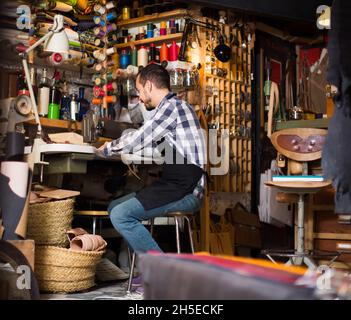 homme travailleur couture de points sur la ceinture dans un atelier de cuir Banque D'Images