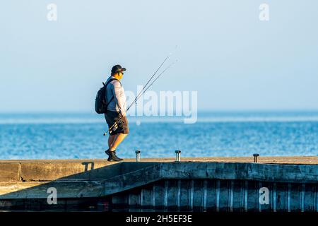 Un seul homme pêchant le long de la jetée au lever du soleil dans un parc local près d'Egg Harbor dans le comté de Door, Wisconsin. Banque D'Images