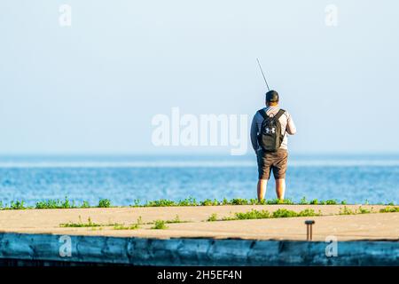 Un seul homme pêchant le long de la jetée au lever du soleil dans un parc local près d'Egg Harbor dans le comté de Door, Wisconsin. Banque D'Images