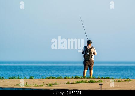 Un seul homme pêchant le long de la jetée au lever du soleil dans un parc local près d'Egg Harbor dans le comté de Door, Wisconsin. Banque D'Images