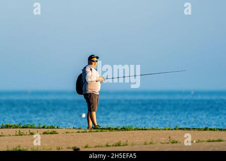 Un seul homme pêchant le long de la jetée au lever du soleil dans un parc local près d'Egg Harbor dans le comté de Door, Wisconsin. Banque D'Images