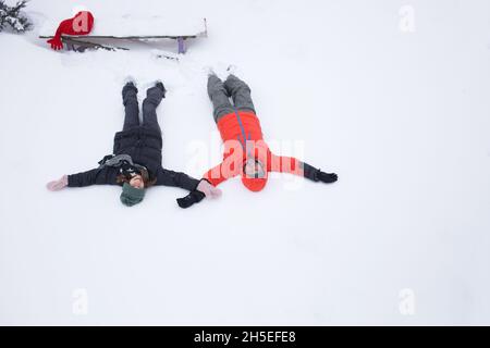 Couple gai, homme et femme dans des vêtements chauds d'hiver, se trouvent dans la neige.Vue de dessus.En hiver, promenades dans la neige, week-ends heureux Banque D'Images