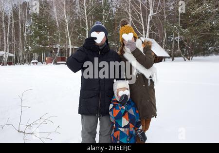 J'adore l'hiver.3 personnes, maman, papa et un petit fils en vêtements d'hiver, tiennent les coeurs en neige devant leur visage.Reposez-vous en hiver, un ac Banque D'Images