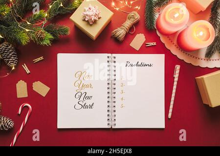 Carnet de résolution de la nouvelle année avec liste de contrôle des objectifs et des trucs de Noël sur fond rouge.Papier vierge, nouveau concept de départ Banque D'Images