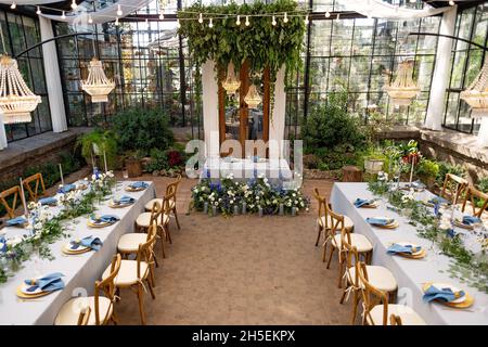 Salle de banquet de mariage dans la serre, les tables sont disposées, décorées avec des fleurs fraîches, des bougies, des lustres en cristal.Mise au point sélective douce. Banque D'Images