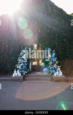 Arche de mariage pour la cérémonie, décorée de roses blanches fraîches, d'orchidées bleues et de bougies.Décor de mariage.Mise au point sélective douce. Banque D'Images
