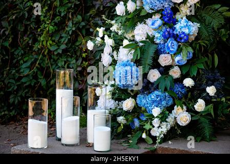 Éléments de décoration de mariage, décorés de roses blanches fraîches, d'orchidées bleues et de bougies.Arc de mariage.Mise au point sélective douce. Banque D'Images