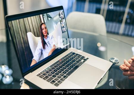 Femme d'affaires méconnue assistant à une visioconférence dans un bureau.Femme d'affaires anonyme utilisant un ordinateur portable pour une réunion virtuelle avec ses partenaires Banque D'Images