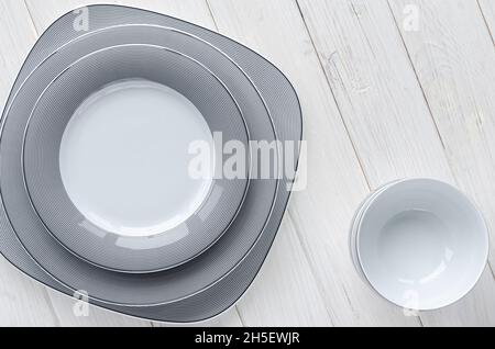 L'ensemble moderne de plaques en porcelaine classique se trouve sur un table en bois blanc Banque D'Images