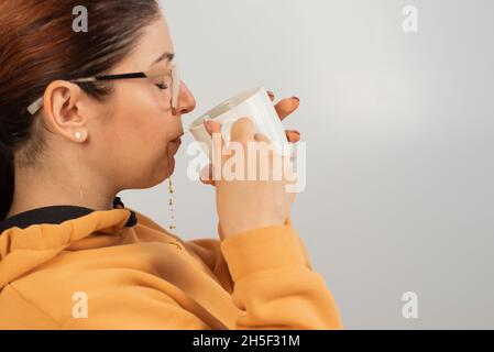 Une femme caucasienne a renversé du café chaud sur elle-même sur fond blanc. Banque D'Images