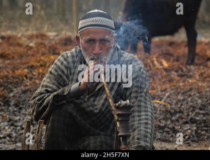 Srinagar, Jammu-et-Cachemire, Inde.9 novembre 2021.Un villageois de Kashmiri fume un tuyau à bulles de hubble alors qu'il prend une pause après avoir épluché la couverture de bâtons d'osier à la périphérie de Srinagar le 11 novembre,2021.osier est utilisé pour faire des pots de feu traditionnels appelés kangri au cachemire.Kashmiris utiliser ces pots de feu traditionnels pour se maintenir au chaud pendant les mois d'hiver sévères quand la température descend à moins 20.Kangri est fait d'argile et de brindilles dans lesquelles le charbon de bois chaud est conservé (Credit image: © Sajad HameedZUMA Press Wire) Banque D'Images