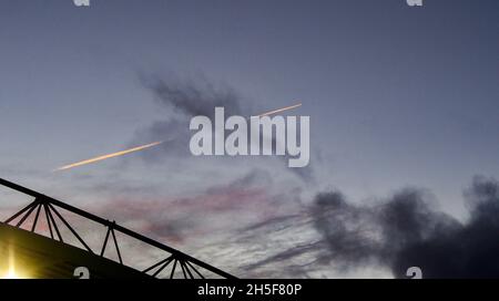 Un avion traverse le ciel au-dessus du stade en laissant une piste de vapeur au coucher du soleil lors du match de la Premier League entre Brighton & Hove Albion et Newcastle United au stade Amex, Brighton, Royaume-Uni - 6 novembre 2021 - Banque D'Images