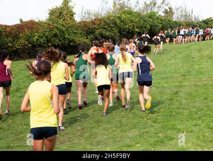 Vue arrière de nombreuses filles de lycée qui s'exécutent en amont sur l'herbe d'une course de fond au parc Bowdoin à Wappingers Falls, New York. Banque D'Images