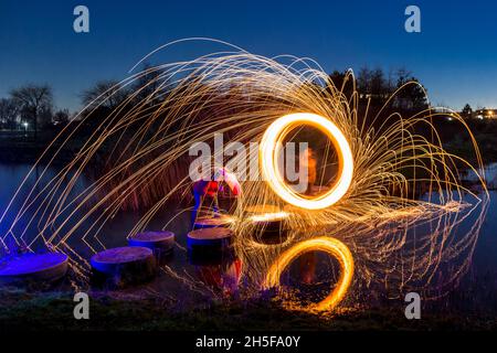 Peinture légère avec laine d'acier; exposition pyrotechnique la nuit.Il pleut la lumière sur le parasol. Banque D'Images