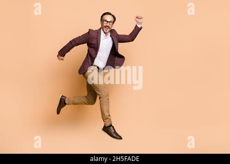 Vue sur toute la longueur de la taille de la gaie attrayante homme saut courir début économiste carrière isolée sur fond beige couleur Banque D'Images