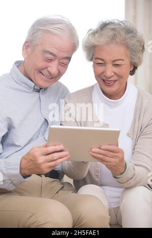 Des couples âgés heureux utilisant des tablettes Banque D'Images