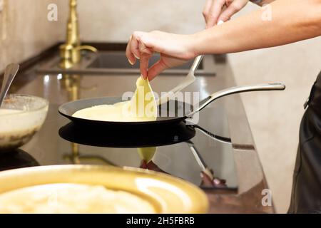 Une femme prépare des crêpes russes dans la cuisine, un gros plan sur une poêle. Le concept de cuisine russe, cuisine, vacances Maslenitsa.Il s'est fait maison Banque D'Images