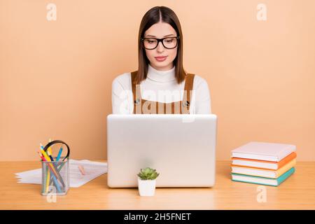 Portrait d'agent de petite fille attirante et spécialisée utilisant un ordinateur portable isolé sur fond beige Banque D'Images