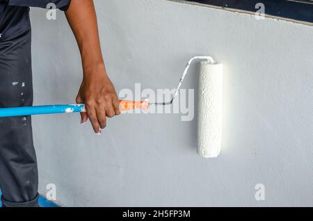 Hommes les peintres utilisent le rouleau de peinture sur le mur blanc. Banque D'Images