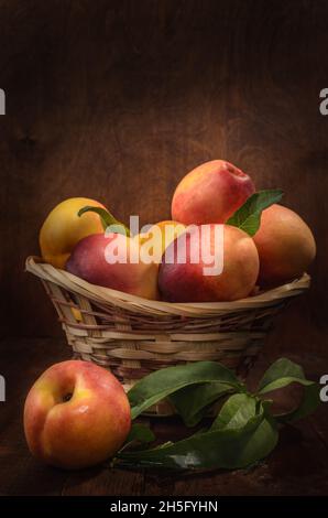 nectarines dans un panier sur fond de bois sombre dans un style rustique Banque D'Images