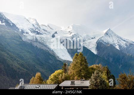 Toits et pins avec des montagnes enneigées en arrière-plan, les alpes françaises au lever du soleil Banque D'Images