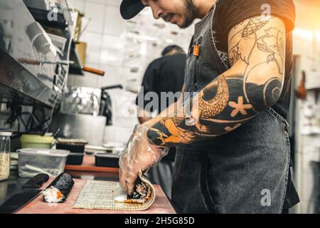 des cuisiniers masculins préparent des sushis dans la cuisine du restaurant. Banque D'Images