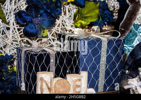 Élégants forfaits paillettes bleues avec ruban doré derrière la bougie Noël et entourés de somptueuses finitions de Noël Banque D'Images