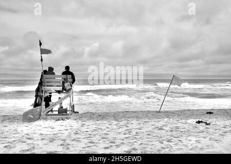 Deux sauveteurs s'assoient sur une chaise de plage en bois pour observer les nageurs sur la plage de long Beach Island, NJ, États-Unis Banque D'Images