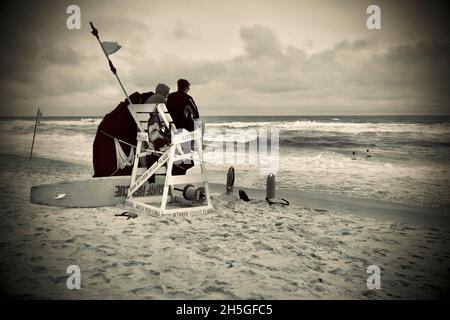 Deux sauveteurs s'assoient sur une chaise de plage en bois pour observer les nageurs sur la plage de long Beach Island, NJ, États-Unis Banque D'Images