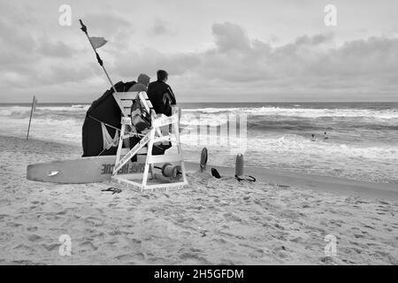 Deux sauveteurs s'assoient sur une chaise de plage en bois pour observer les nageurs sur la plage de long Beach Island, NJ, États-Unis Banque D'Images