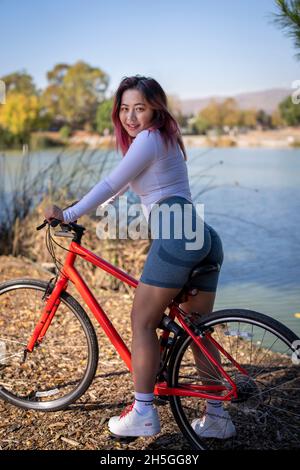 Vue arrière de la jeune femme asiatique Biker assis au bord du lac Banque D'Images