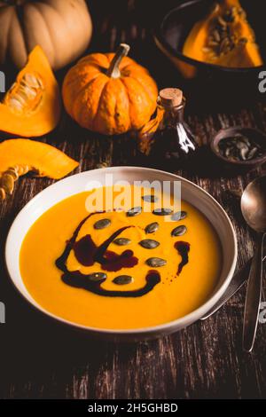 Soupe de potiron maison avec huile de potiron et graines sur fond de bois Banque D'Images