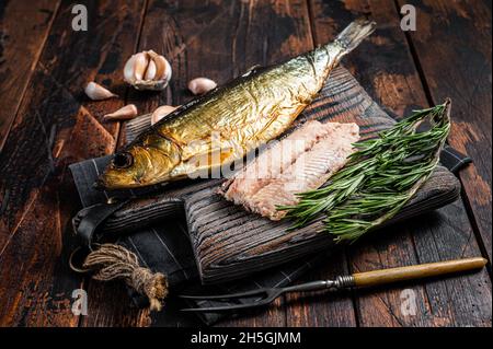 Filet de poisson fumé parfumé au hareng sur planche de bois aux herbes.Arrière-plan en bois.Vue de dessus Banque D'Images